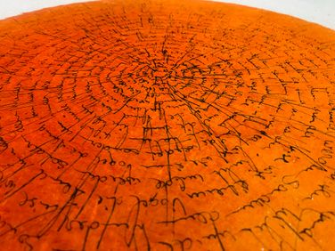Schriftbild auf orangem und weissem Büttenpapier