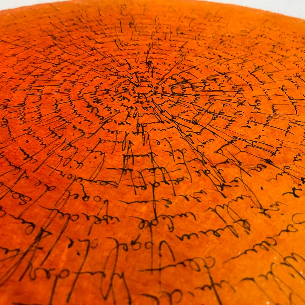 Schriftbild auf orangem und weissem Büttenpapier